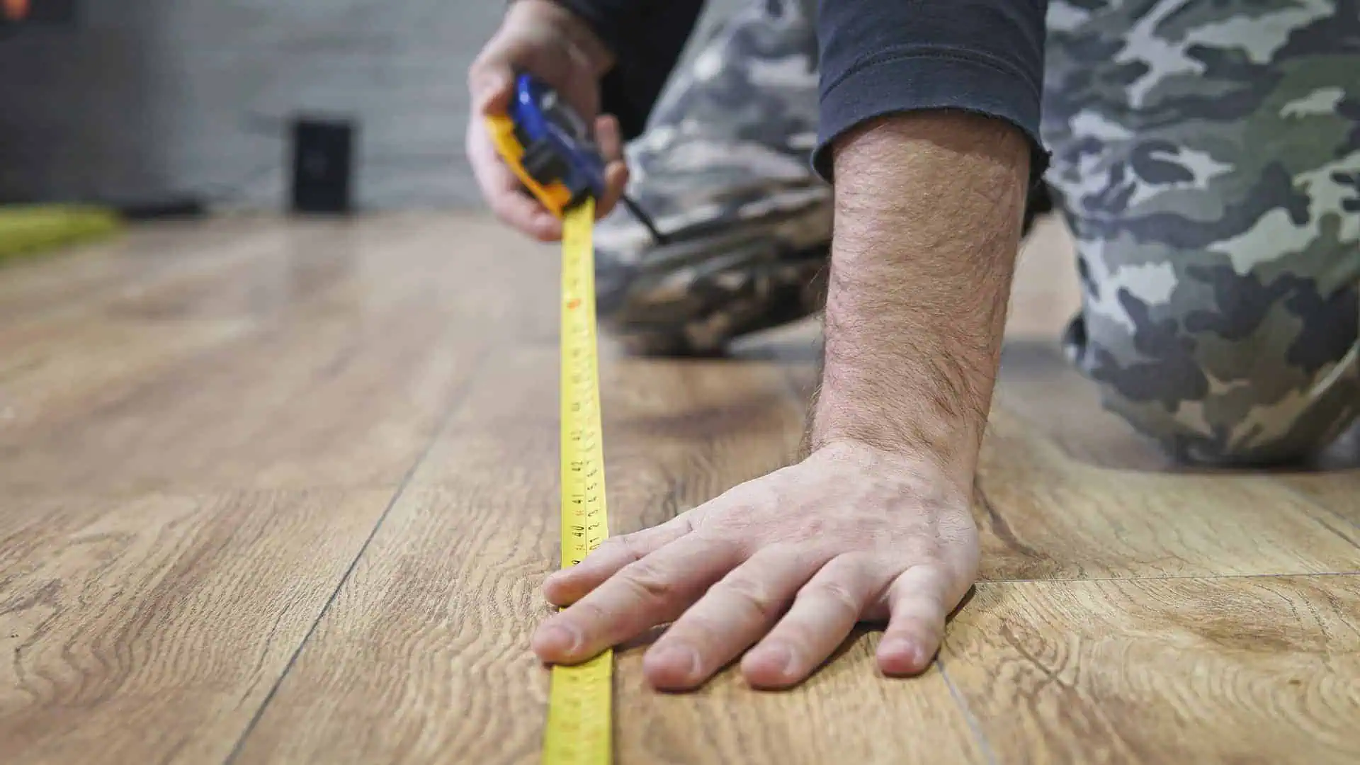 Man using a tape measure to measure a room for new flooring or underlay