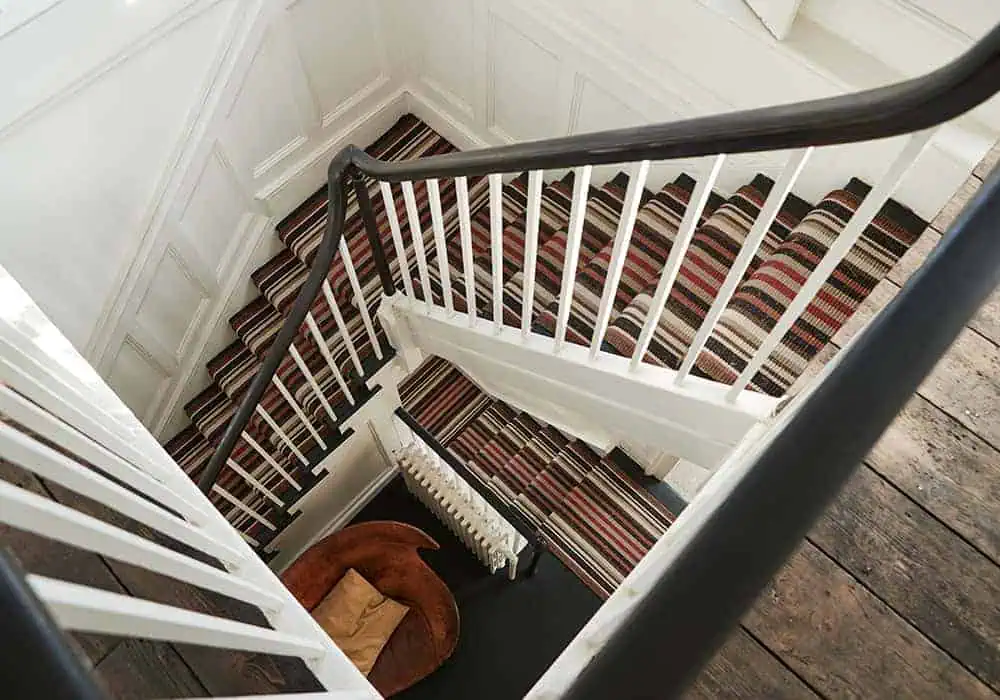 A set of stairs with a striped stair runner installed over underlay