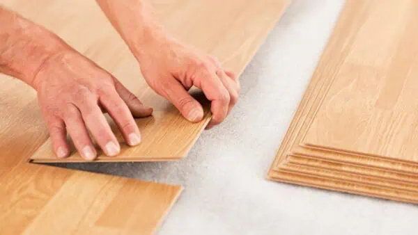 Man installing laminate underlay over white pu foam underlay