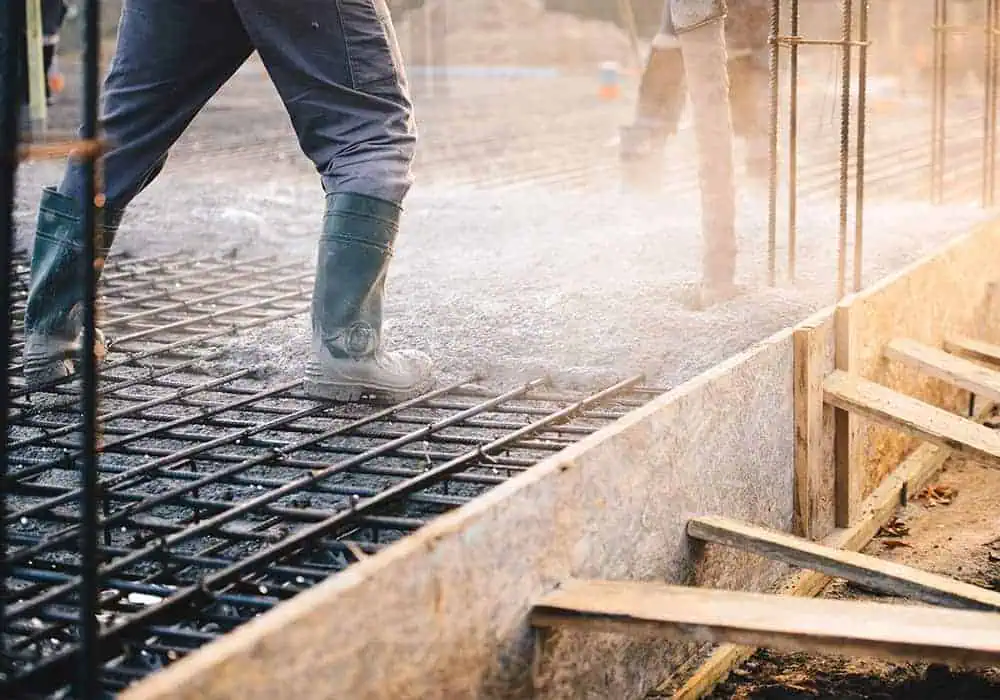 Workers pouring a concrete subfloor for a building