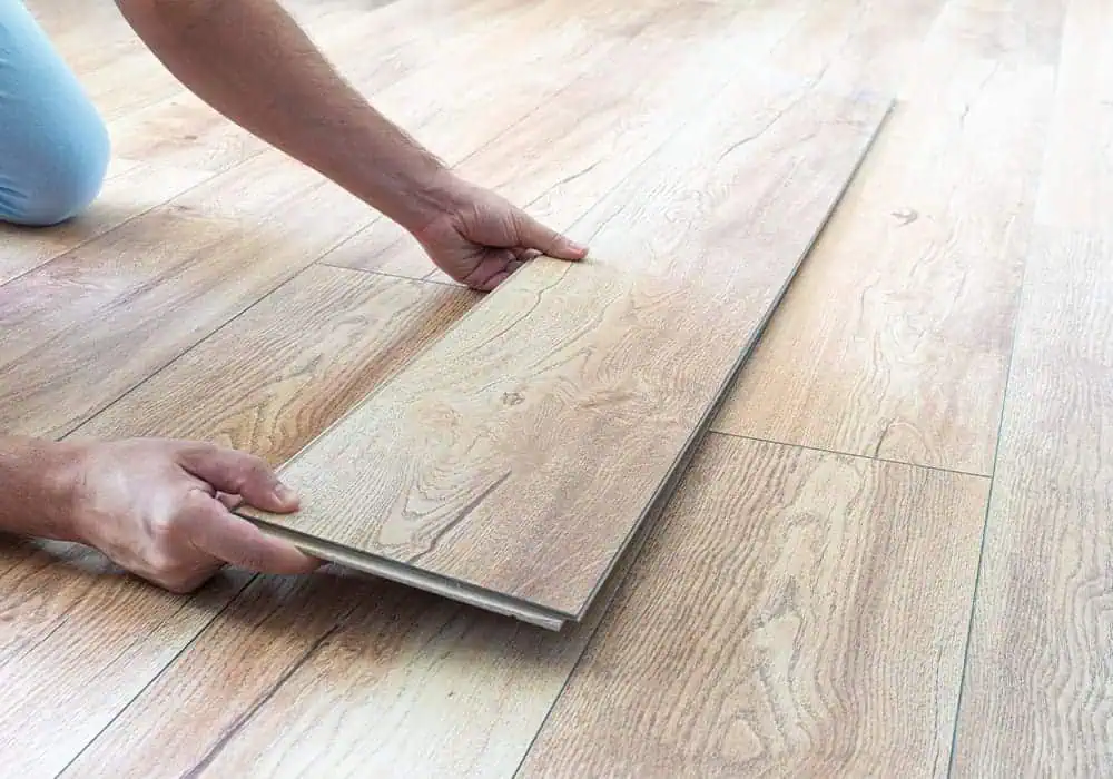 Man holding laminate flooring plank to show thickness