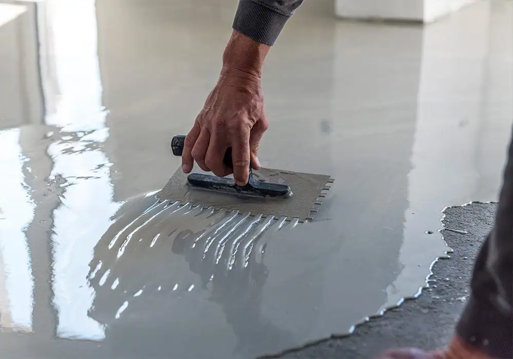 Man applying self-levelling screed to a concrete floor