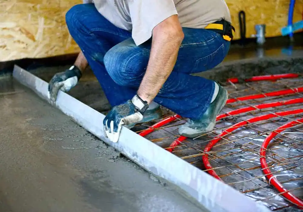 Man installing a concrete subfloor over underfloor heating pipes in a wet system