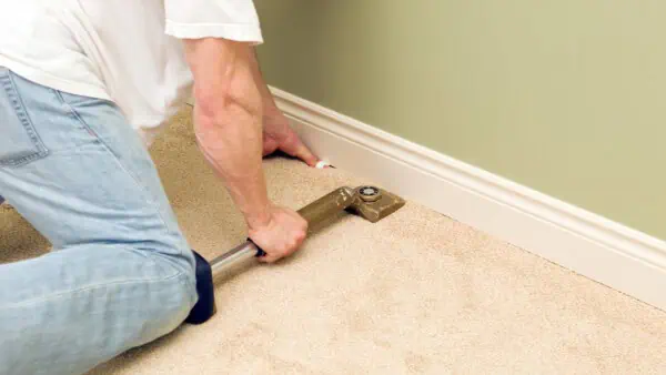 Man fitting a carpet using a knee kicker