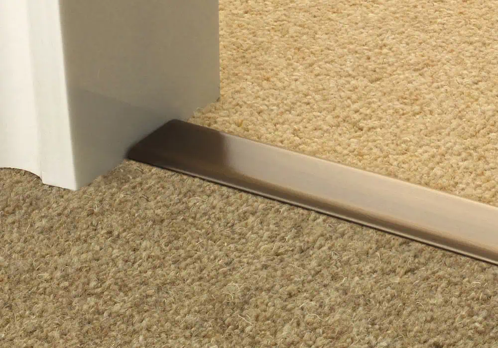 Dual edge door bar in antique brass transitioning from carpet to carpet