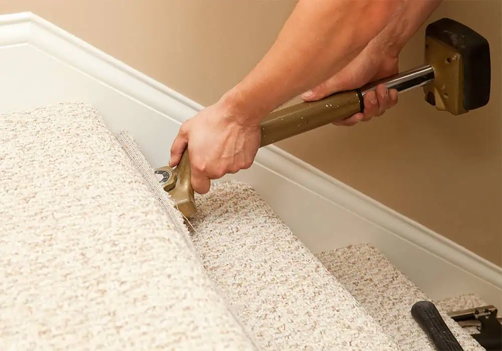 Man installing stairs carpet with a knee kicker