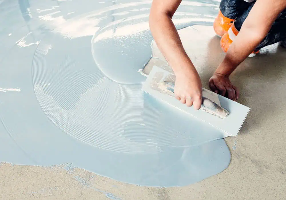 Man applying self-levelling compound to a concrete subfloor