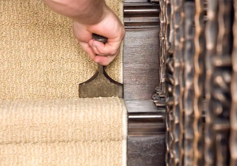 Man using a bolster to fit a carpet stair runner