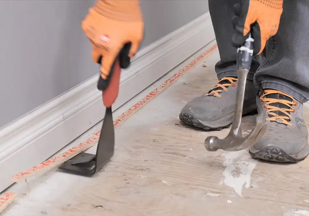 Man removing old carpet gripper with a pry bar