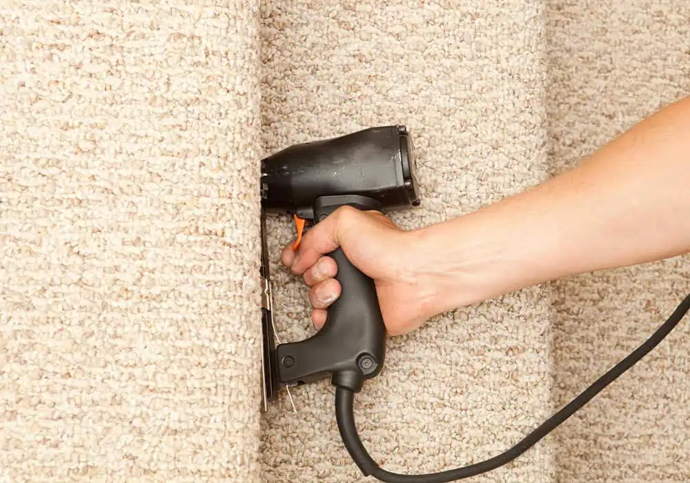 Man fixing a stair runner to the stairs using a staple gun