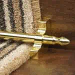 Homepride Stair Carpet Runner Rod in shiny Brass with a striped carpet on wooden stairs