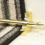 Homepride Stair Carpet Runner Rod in Shiny Brass with a striped carpet on light wood stairs